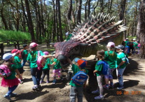 Dzieci głaszczą dinozaura z kolcami.